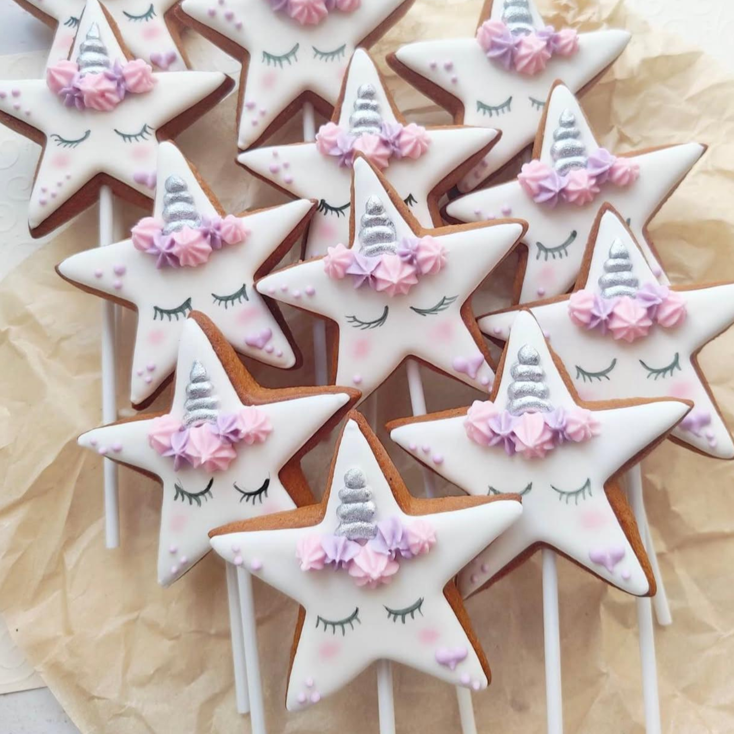 Handgemachte Lebkuchen in Sternform mit Einhorn-Design von Ginger Glow – verziert mit pastellfarbenem Zuckerdekor und silbernem Horn, hergestellt in Wien.