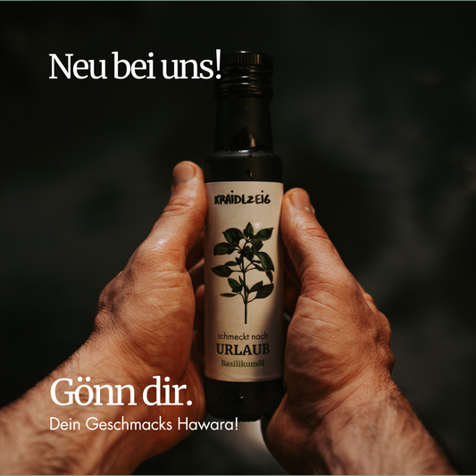 Hände halten eine Flasche Bio-Basilikumöl von Kräidlzeig mit der Aufschrift ‚schmeckt nach Urlaub‘ – neues Kräuteröl im Sortiment, regional und nachhaltig produziert